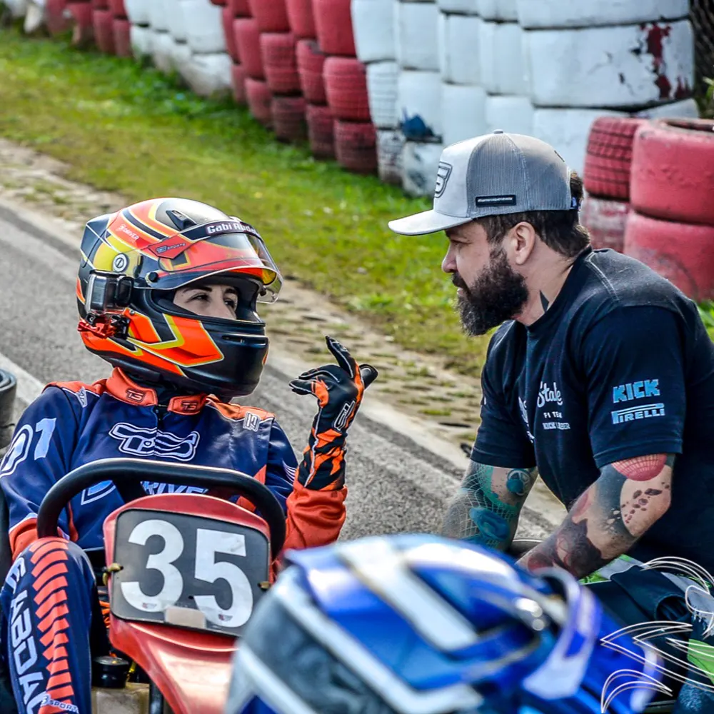 Gabrielle Abdala de capacete no kart 35 conversando com o Diêgo no box